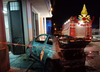 Paura nel centro abitato: auto in fiamme si schianta contro il portone di una falegnameria